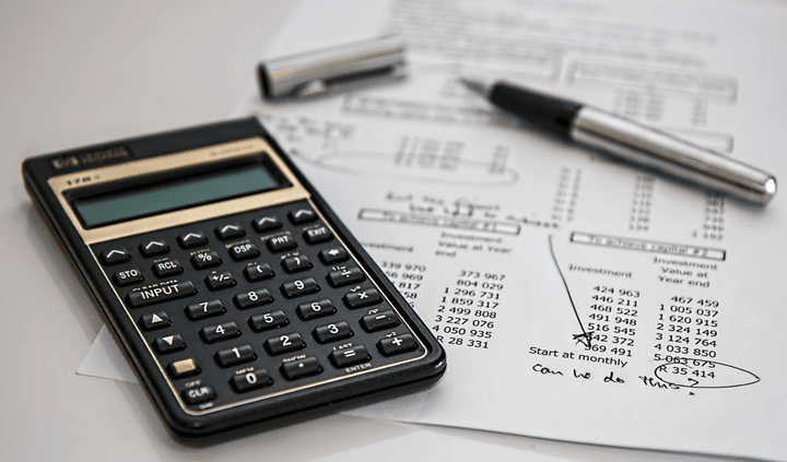 Calculator and financial documents used to compare car insurance quotes and premiums for budgeting vehicle coverage costs.