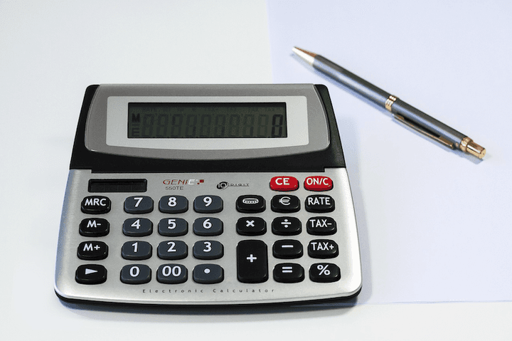 A calculator and pen on a desk.
