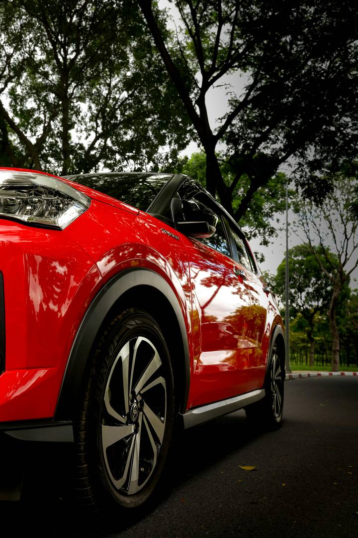 Low-angle view of a red Toyota Yaris Cross SUV with a black bi-tone roof and turbine-style alloy wheels.