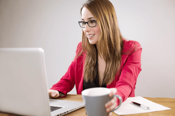 A woman using a laptop while drinking coffee.