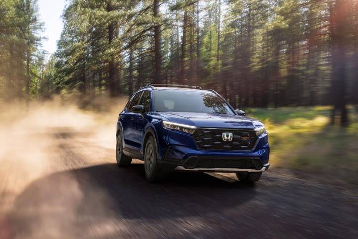 A blue 2026 Honda CR-V driving on a dusty forest road.