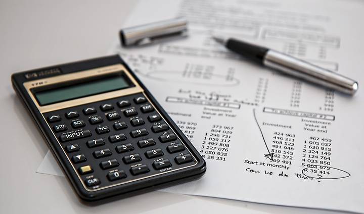 A calculator, pen, and financial papers with "can we do this" written on them.