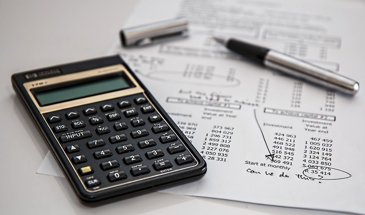 A calculator, pen, and financial papers with "can we do this" written on them.