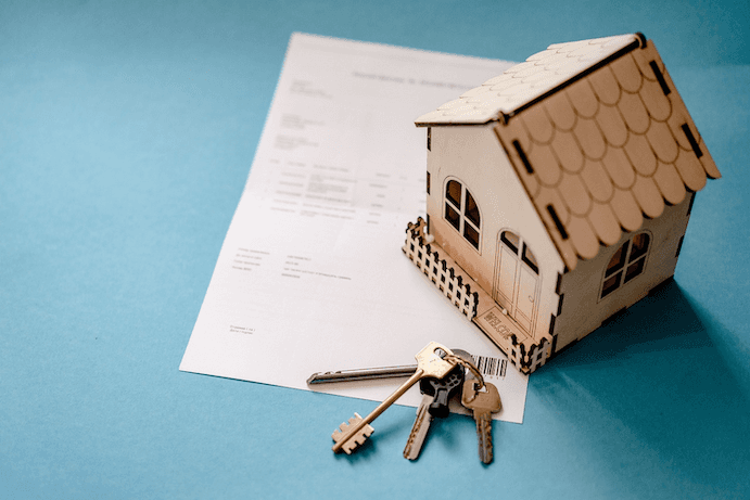 A model house with keys on an insurance document.