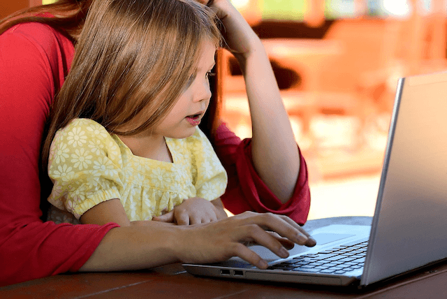 A person using a laptop with daughter. 