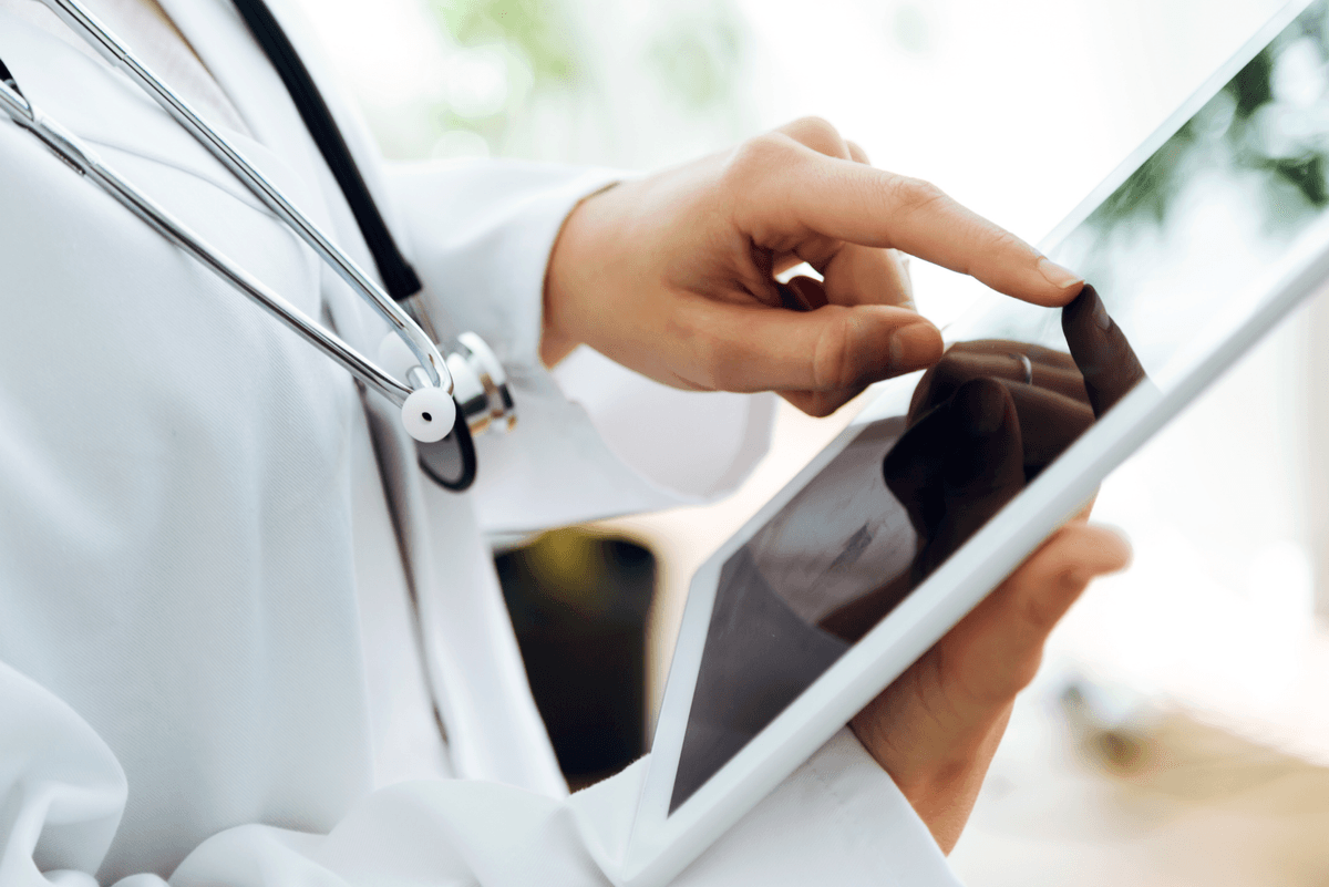 A doctor using a tablet to complete a medical assessment.