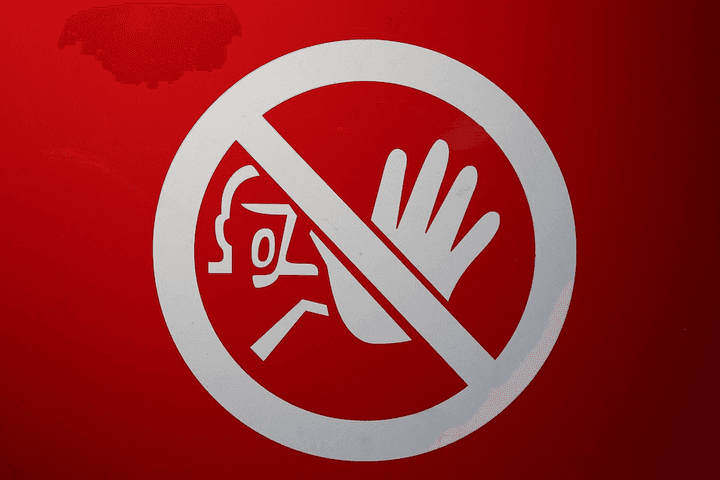A red "stop" symbol with a hand, representing the common exclusions and conditions in NZ car insurance policies that could reduce or void cover while a vehicle is parked at Auckland Airport in 2026.