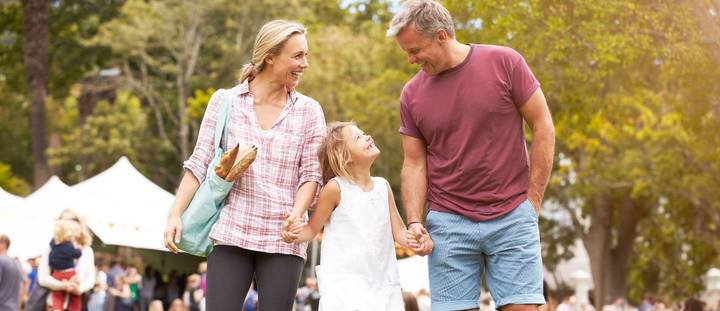 A mother and father holding their daughters hands.