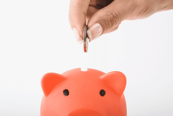 Hand inserting a coin into a piggy bank, representing the $300+ average contents insurance savings found by the Quashed Market Scan in 2025.