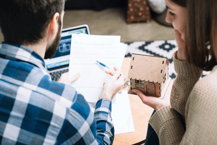 A New Zealand couple reviewing their insurance renewal documents at a kitchen table.