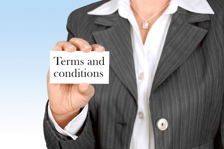 A New Zealand woman holding a terms and conditions sign, illustrating consumer rights when a car wash damages your vehicle.