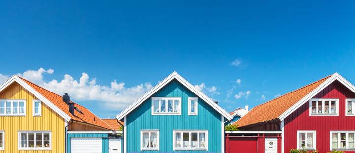Vibrant wooden houses in New Zealand under a clear blue sky.